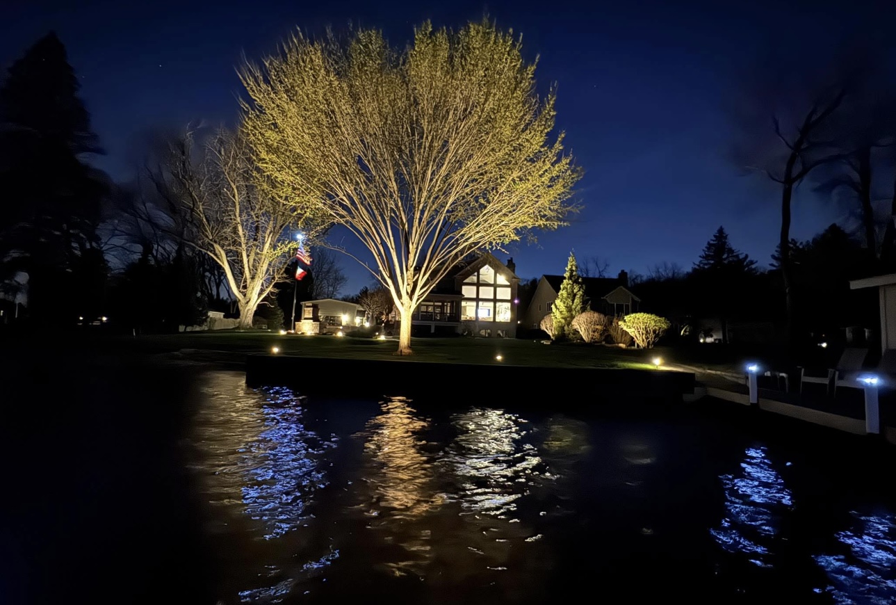 Waterfront home with warm architectural and landscape lighting plus cool white dock lights