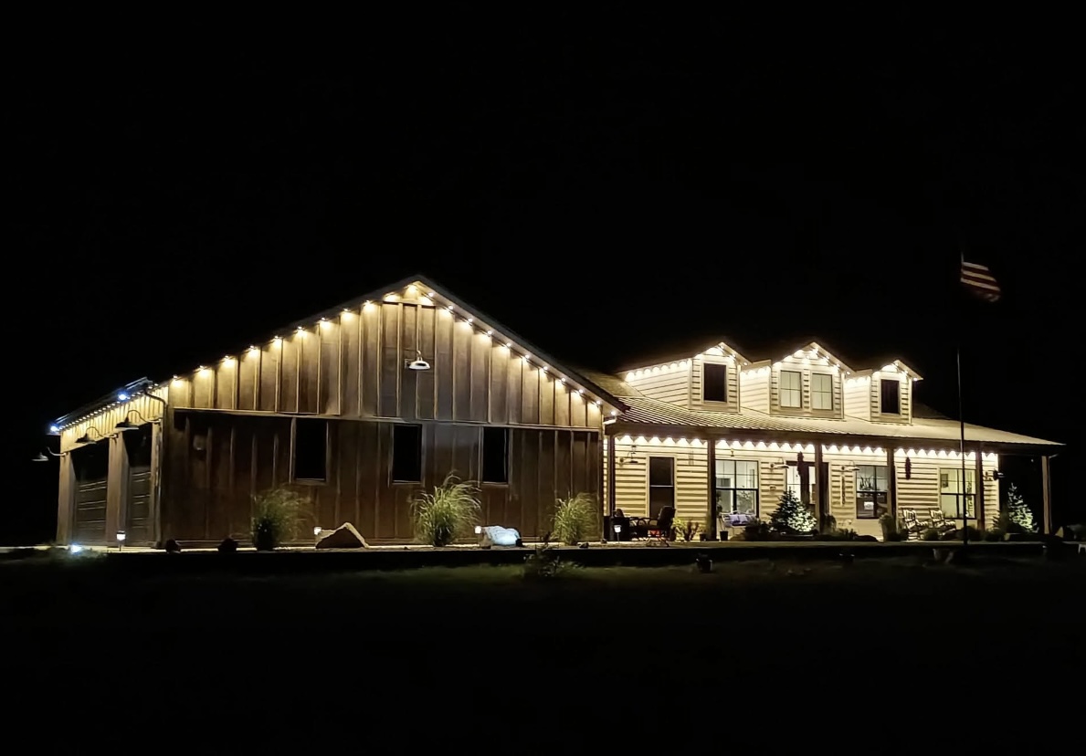 Ranch home and shop in warm white holiday lights at night